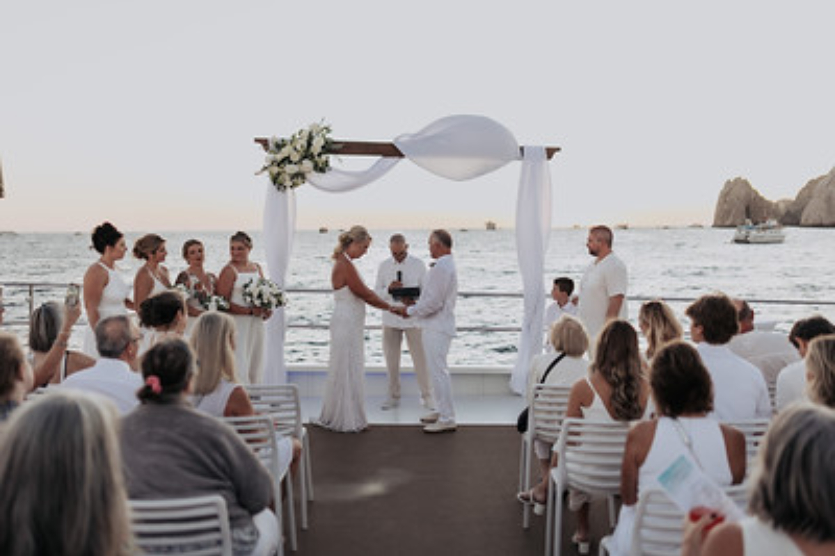 A wedding ceremony on a catamaran deck with the Arch in the background