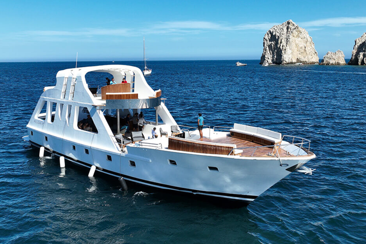 Large event boat with an open bow deck cruising off the Land's End rocks in Cabo