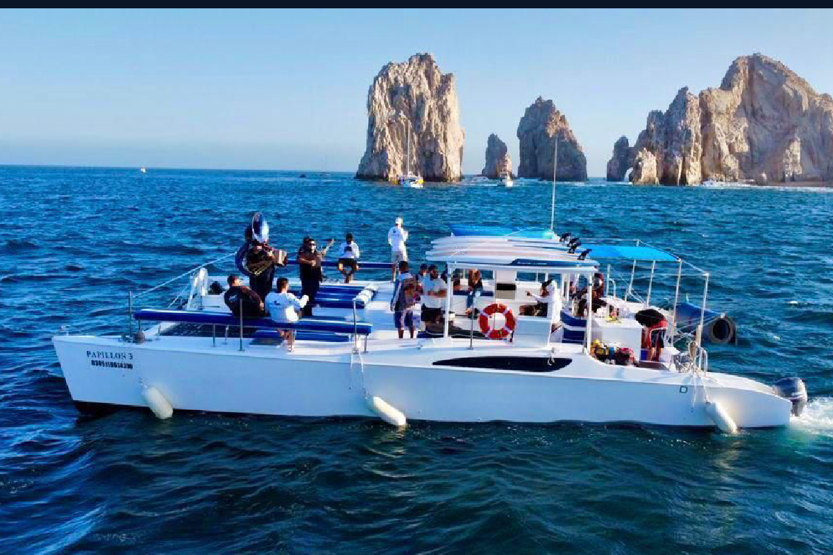 Party catamaran with guests and musicians on board off the Land's End rock formations