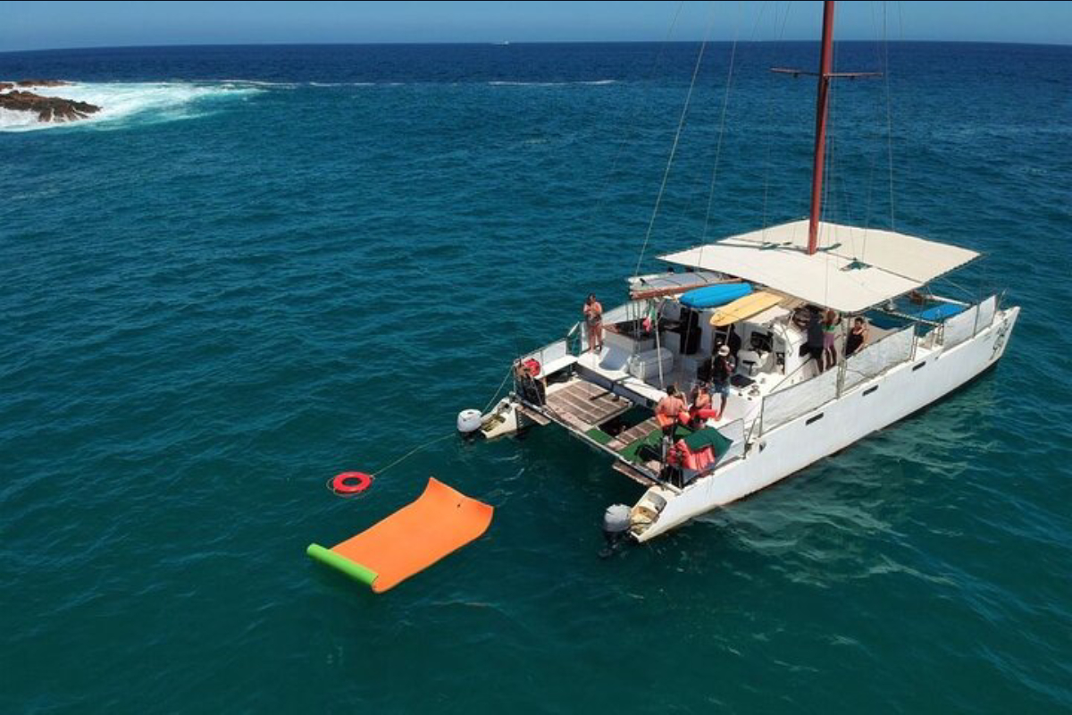 Catamaran at anchor with a floating swim mat in clear water off Cabo San Lucas