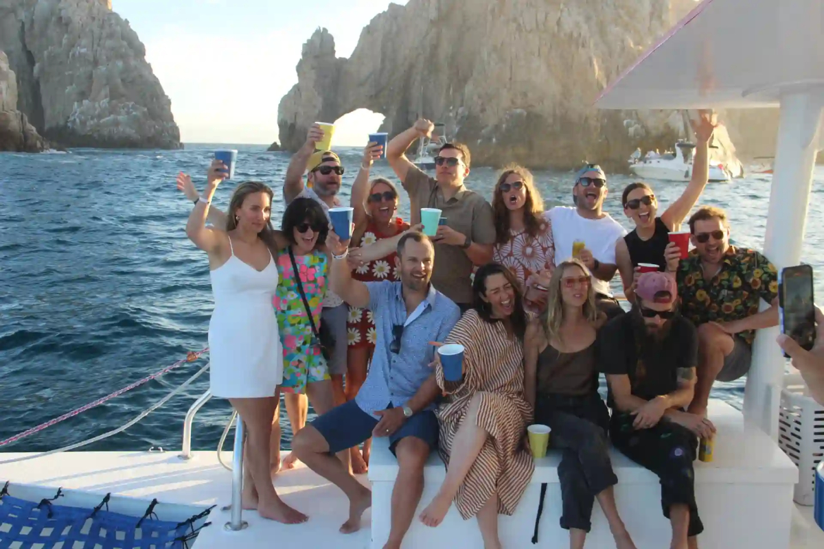 A celebration group raising glasses on a catamaran in front of the Arch