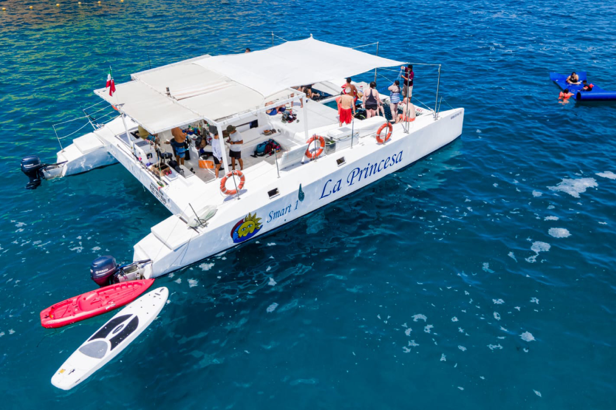 Aerial view of a luxury catamaran with paddleboards alongside in clear Cabo water