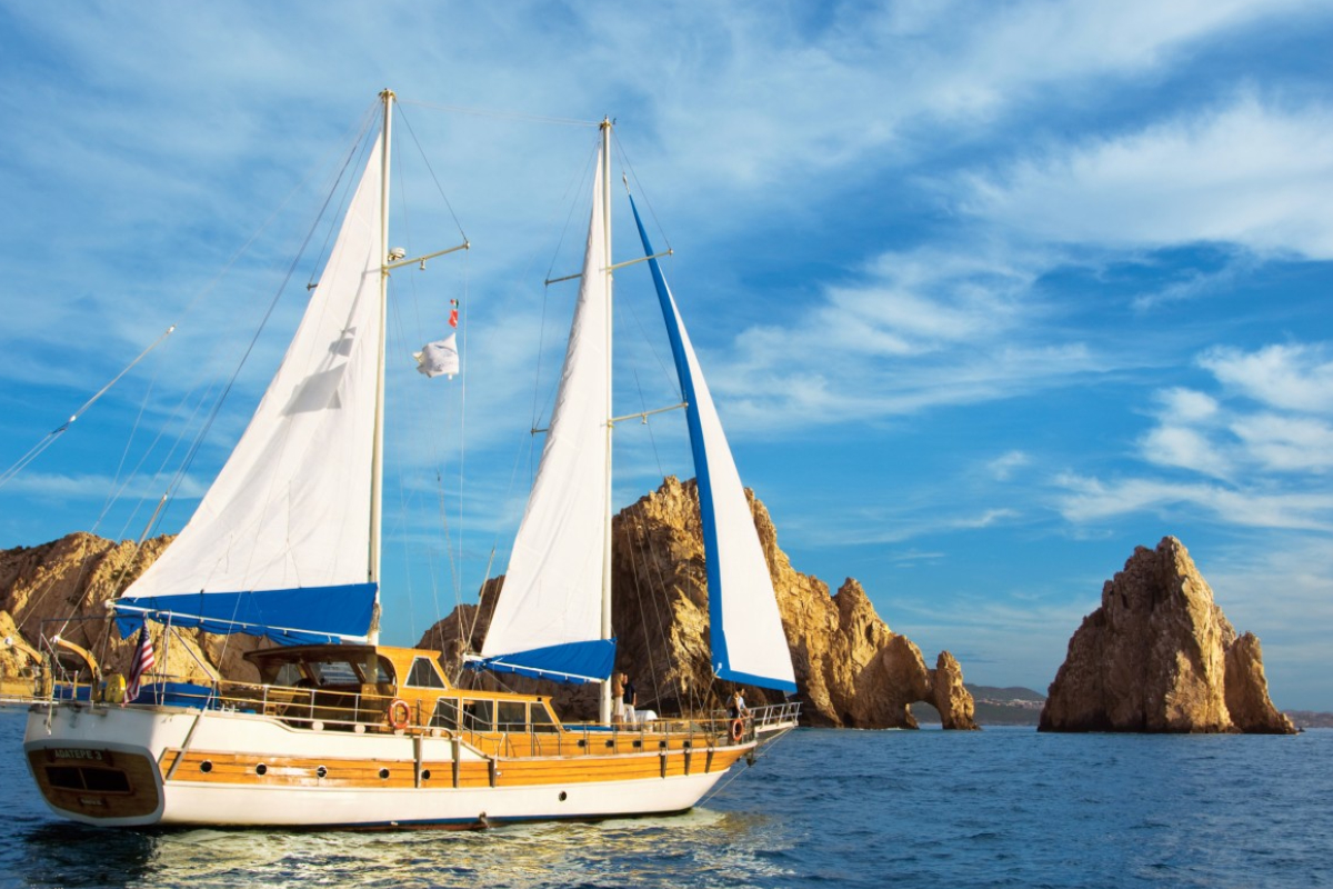 Sailing yacht under full sail cruising past the Arch at Land's End in Cabo San Lucas