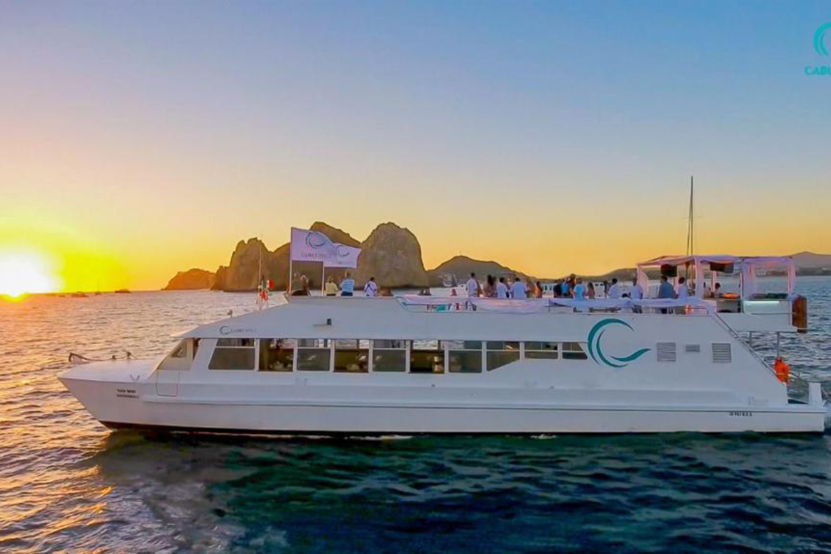 Event boat with guests on the upper deck at sunset in Cabo San Lucas