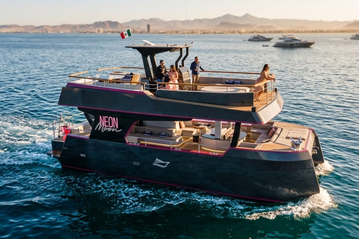 Guests cruising on a private luxury catamaran along the Los Cabos coastline at golden hour