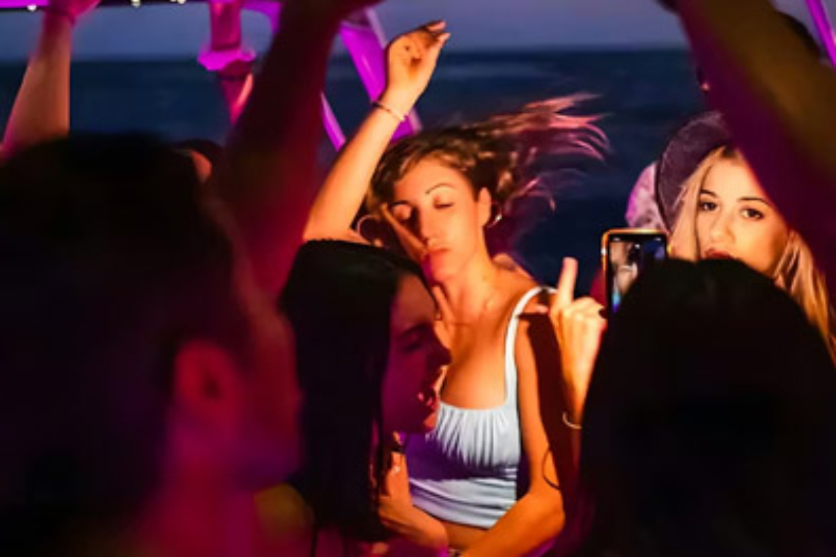 Guests dancing under pink club lighting on a night charter in Cabo